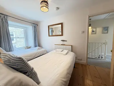 two beds in a room with a window and a mirror at Seabreeze in St Ives