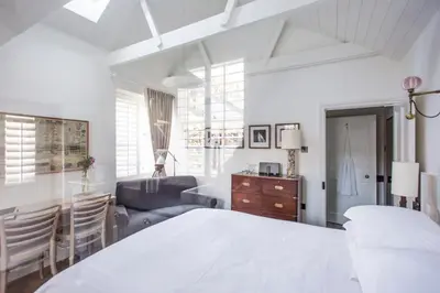 a white bedroom with a bed and a living room at Antonia's Pearls in St Austell