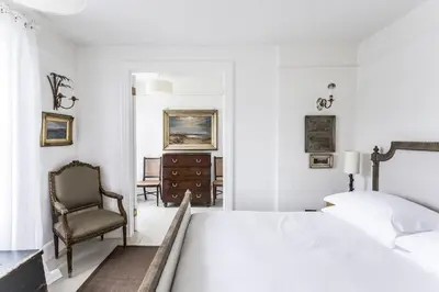 a white bedroom with a bed and a chair at Antonia's Pearls in St Austell