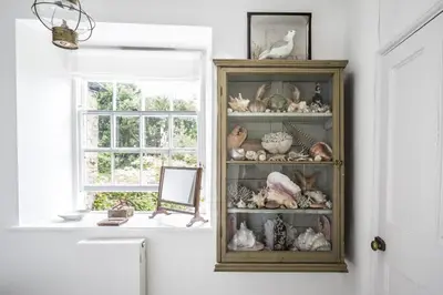 a cabinet filled with lots of stuffed animals next to a window at Antonia's Pearls in St Austell