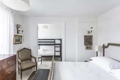 a white bedroom with a bed and a chair at Antonia's Pearls in St Austell