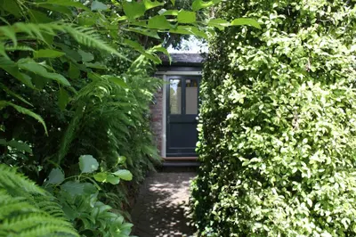 a door through a hedge with a walkway at Antonia's Pearls in St Austell