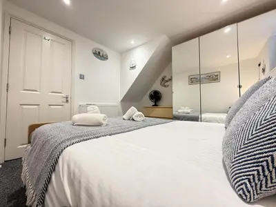 a bedroom with a large white bed with a mirror at Pennys Place in St Ives