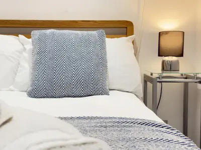 a bed with a blue and white pillow on it at Pennys Place in St Ives
