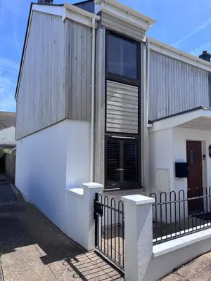 a white house with a black window and a fence at Boho Bali-style Beach House near Fistral in Newquay