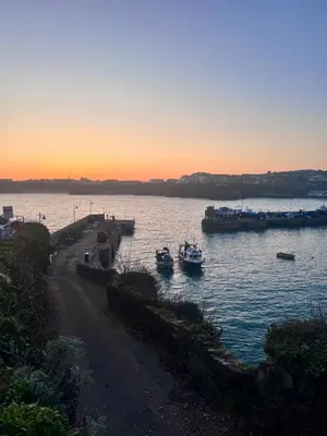 a boat in a body of water at sunset at Boho Bali-style Beach House near Fistral in Newquay