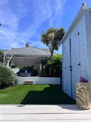 a house with a white garage and a palm tree at Boho Bali-style Beach House near Fistral in Newquay