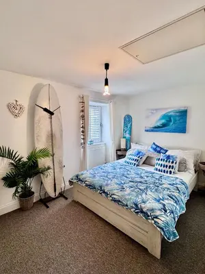 a bedroom with a surfboard next to a bed at Boho Bali-style Beach House near Fistral in Newquay