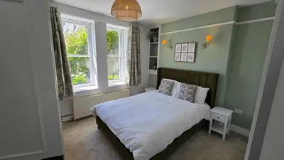 a small bedroom with a bed and two windows at Headmasters House in Port Isaac