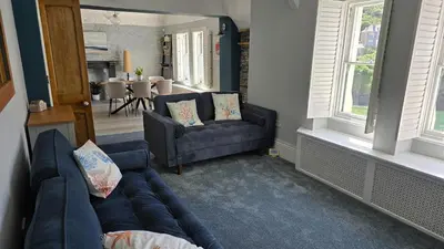 a living room with a couch and a chair and windows at Headmasters House in Port Isaac