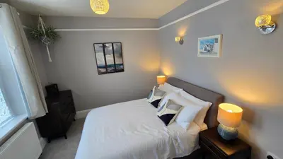 a bedroom with a bed with white sheets and pillows at Headmasters House in Port Isaac