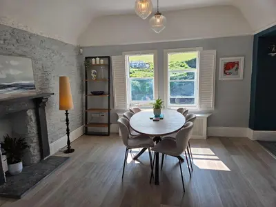 a dining room with a table and chairs and a fireplace at Headmasters House in Port Isaac
