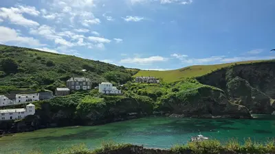 a group of houses on a hill next to a body of water at Headmasters House in Port Isaac