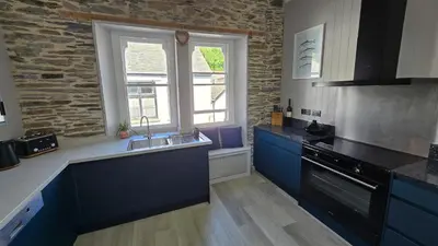 a kitchen with blue cabinets and a sink and a window at Headmasters House in Port Isaac
