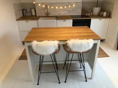 a kitchen with a wooden counter with two bar stools at Entire Apartment in Pretty Coastal Village in Cubert
