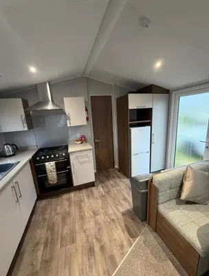 a kitchen with a couch and a kitchen with a stove at Haven Holiday Park Perran Sands in Perranporth