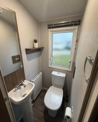 a bathroom with a toilet and a sink and a window at Haven Holiday Park Perran Sands in Perranporth