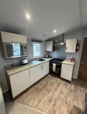 a kitchen with white cabinets and a stove top oven at Haven Holiday Park Perran Sands in Perranporth