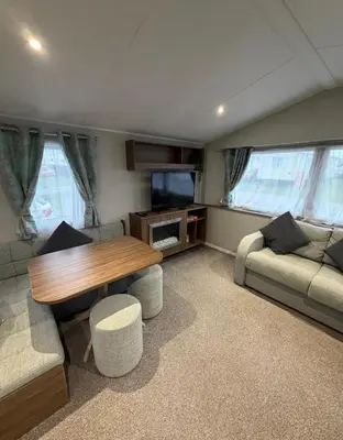 a living room with a table and a couch at Haven Holiday Park Perran Sands in Perranporth