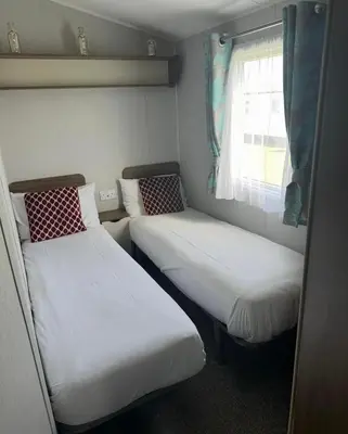 two beds in a small room with a window at Haven Holiday Park Perran Sands in Perranporth