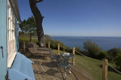 a balcony with a table and chairs on a house at Shepherd's Hut Gorran Haven Panoramic Ocean Views in Gorran Haven