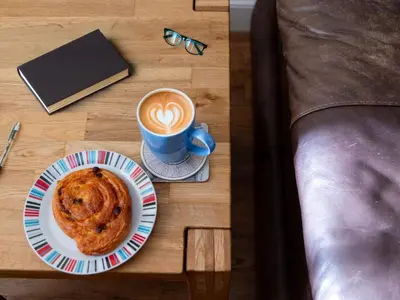 a table with a plate of pastry and a cup of coffee at Holiday Home Porthilly by Interhome in Mevagissey