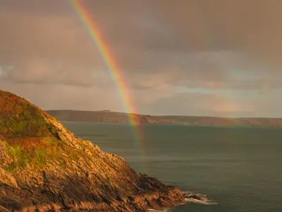 a rainbow in the sky over the water at Holiday Home Porthilly by Interhome in Mevagissey