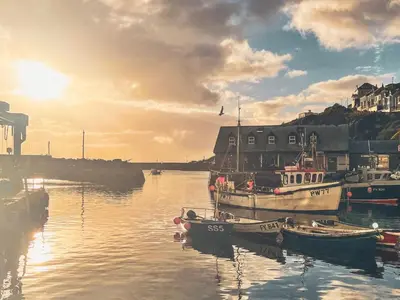 a group of boats docked in a harbor with the sunset at Holiday Home Porthilly by Interhome in Mevagissey