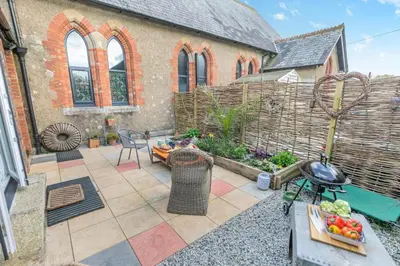 a patio with a table and a grill in front of a building at 1 Bed in Menheniot oc-t29268 in Menheniot