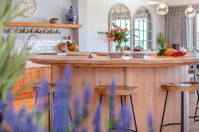 a kitchen with a large wooden counter with stools at 5 Bed in Polzeath oc-r33648 in Polzeath