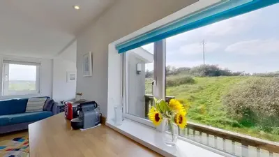 a living room with a window with a vase of flowers at G22 Happy Days, Riviere Towans in Hayle