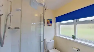 a bathroom with a shower and a toilet and a window at G22 Happy Days, Riviere Towans in Hayle