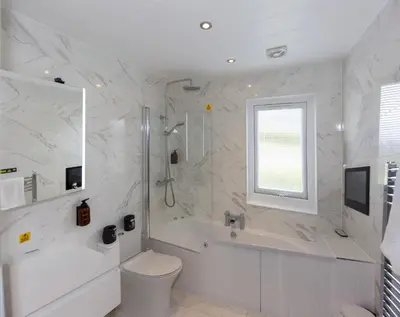 a white bathroom with a tub and a toilet and a sink at Dahlia in Redruth