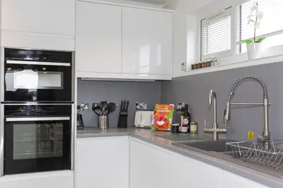 a kitchen with white cabinets and a sink at Dahlia in Redruth