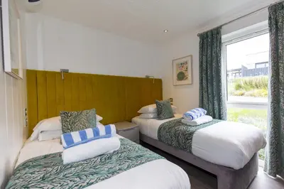 two beds in a room with a window at Dahlia in Redruth