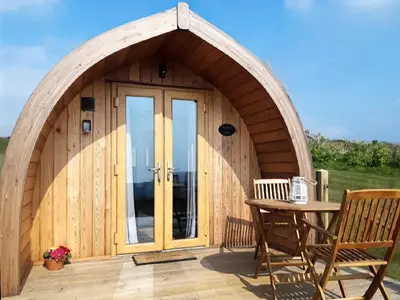 a wooden cabin with an arched door and a table at Scenic Bay in Penzance
