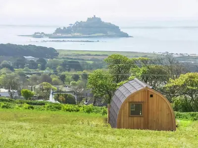 a wooden shed in a field with an island in the distance at Scenic Bay in Penzance