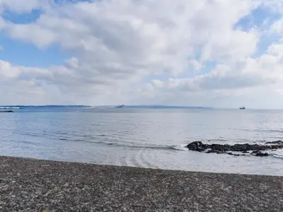 a beach with a body of water and a cloudy sky at Scenic Bay in Penzance