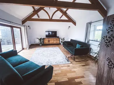 a living room with a couch and a tv at The Retreat Cornwall holiday home with hot tub in Crowan