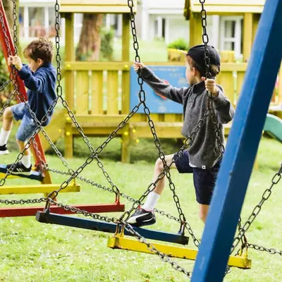 two young children playing on a swing set at Dog Friendly Holiday Home in Newquay Cornwall in Newquay