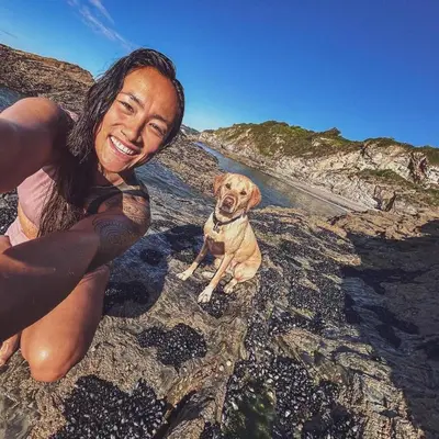 a woman and a dog sitting on the beach at Dog Friendly Holiday Home in Newquay Cornwall in Newquay