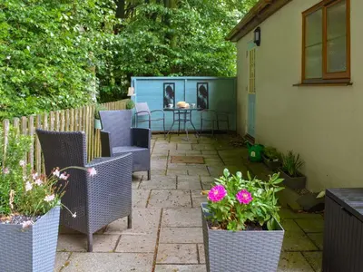 a patio with chairs and a table and some flowers at Kingfisher Cottage, 20 in Camelford