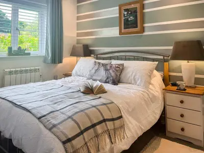 a bedroom with a bed with a book on it at Kingfisher Cottage, 20 in Camelford