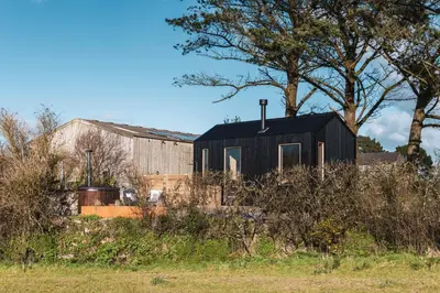 a black house sitting on top of a field at Cabins at Bogee Farm in Saint Ervan