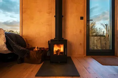 a wood stove in a room with a window at Cabins at Bogee Farm in Saint Ervan