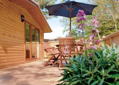 a patio with a table and chairs and an umbrella at Landal Leycroft Valley in Perranzabuloe
