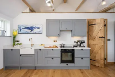 a kitchen with white cabinets and a wooden door at Skylark in Bodmin