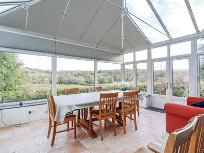 a dining room with a table and chairs and windows at Tresarrett Manor in Bodmin