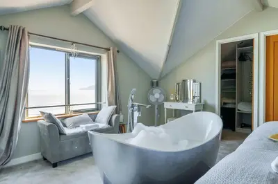 a bathroom with a tub and a chair and a window at Lightkeepers Cottage in Charlestown