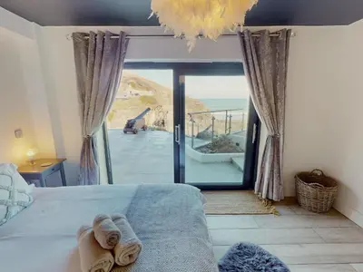 a bedroom with a bed and a large glass door at The Tide House in Portreath